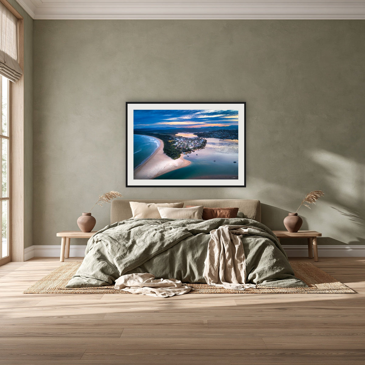 Fishpen on Dusk framed print in black with a white mat, above a khaki linen bed against a green-grey wall in a bedroom