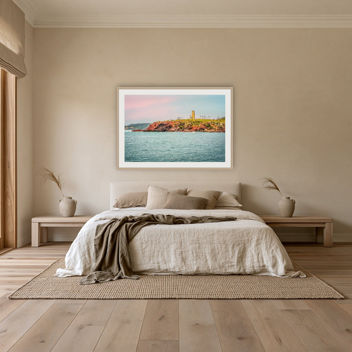 Ben Boyd Tower Seascape framed print in oak with a white mat, above an oatmeal linen bed in a bedroom
