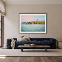 Ben Boyd Tower Seascape framed print in black with a white mat, above a navy linen sofa in a lounge room