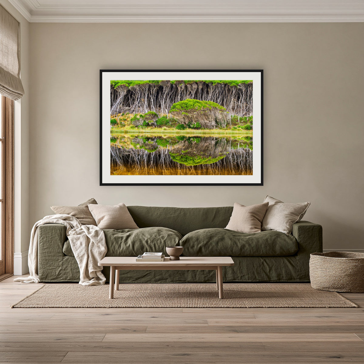 Bournda Lagoon Reflections framed print in black with a white mat, above an olive linen sofa in a lounge room