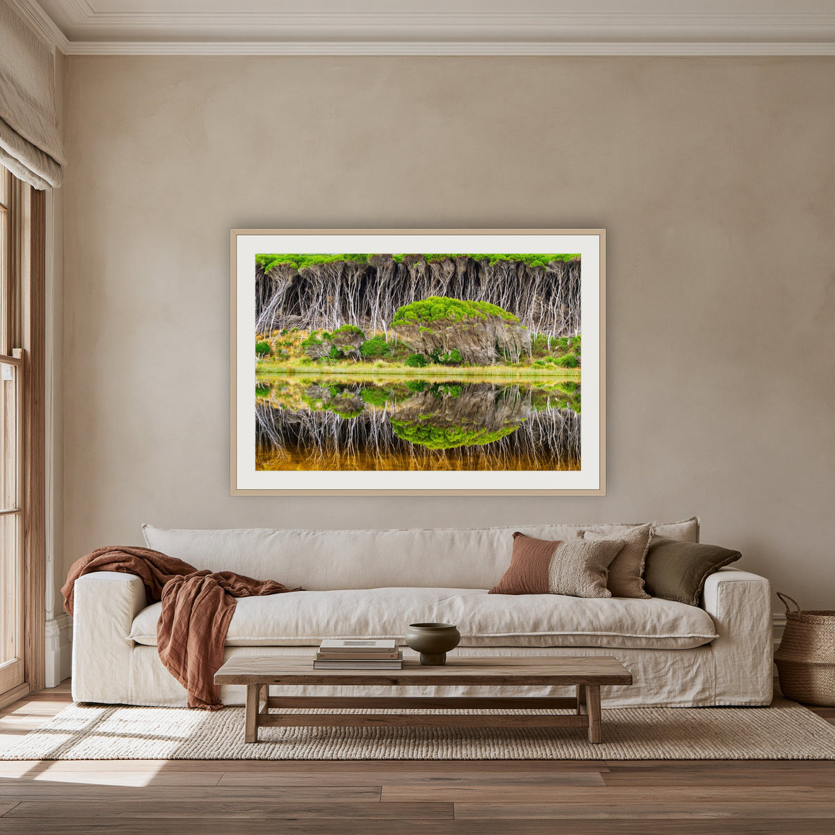 Bournda Lagoon Reflections framed print in oak with a white mat, above an oatmeal linen sofa in a lounge room