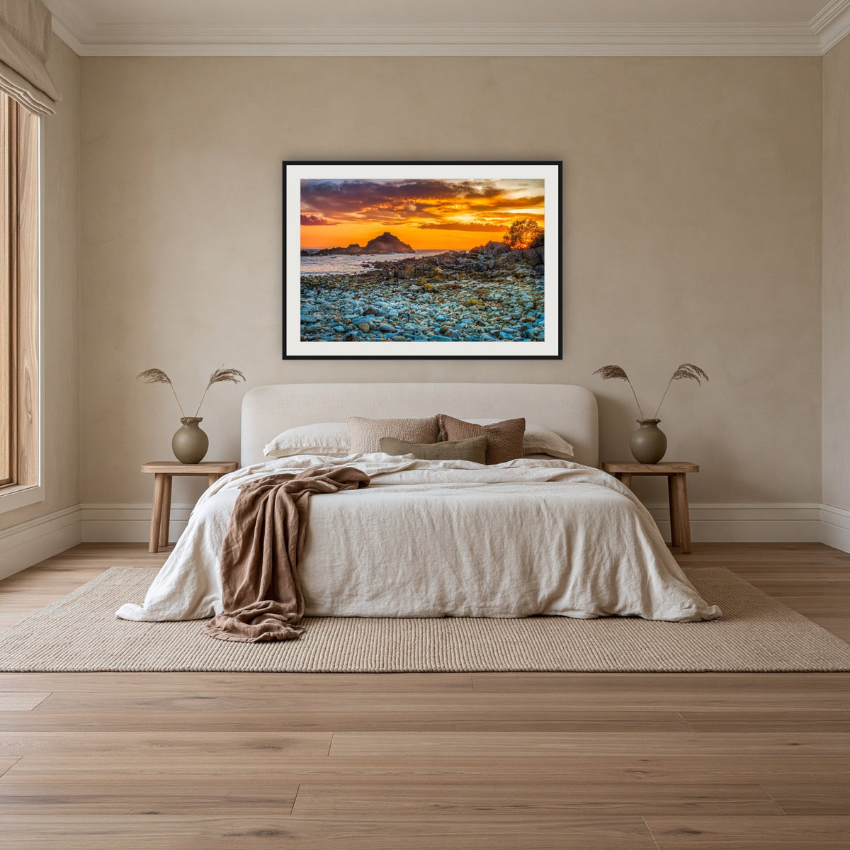 Mimosa Rocks Sunrise framed print in black with a white mat, above an ivory linen bed in a bedroom