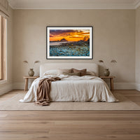 Mimosa Rocks Sunrise framed print in black with a white mat, above an ivory linen bed in a bedroom