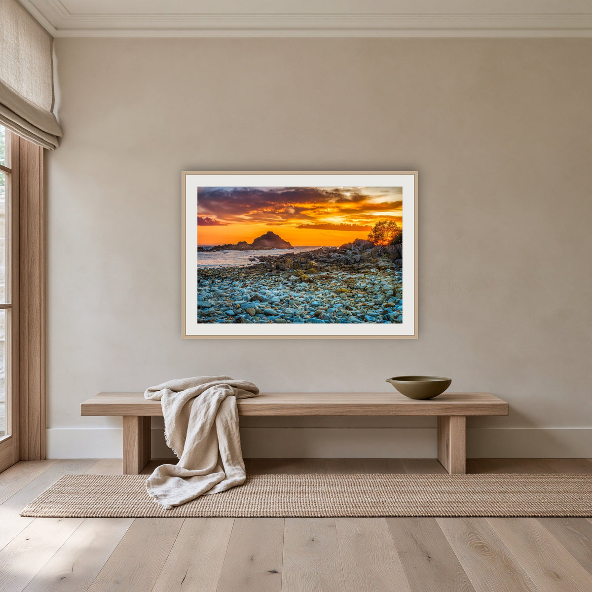 Mimosa Rocks Sunrise framed print in oak with a white mat, above an oak bench in a hallway