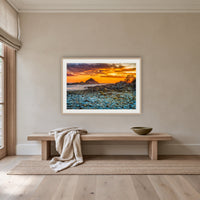 Mimosa Rocks Sunrise framed print in oak with a white mat, above an oak bench in a hallway