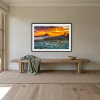 Mimosa Rocks Sunrise framed print in black with a white mat, above an oak bench in a hallway
