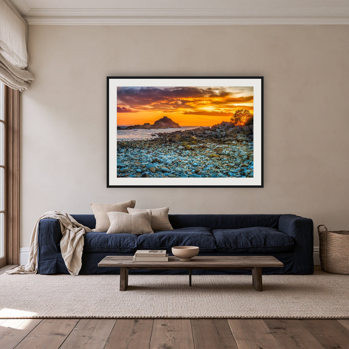 Mimosa Rocks Sunrise framed print in black with a white mat, above a navy linen sofa in a lounge room