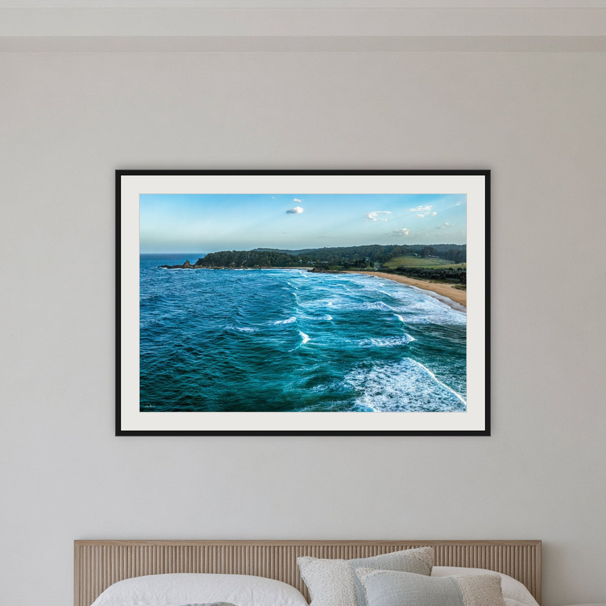 Cuttagee Beach framed print in black with a white mat, in a bedroom