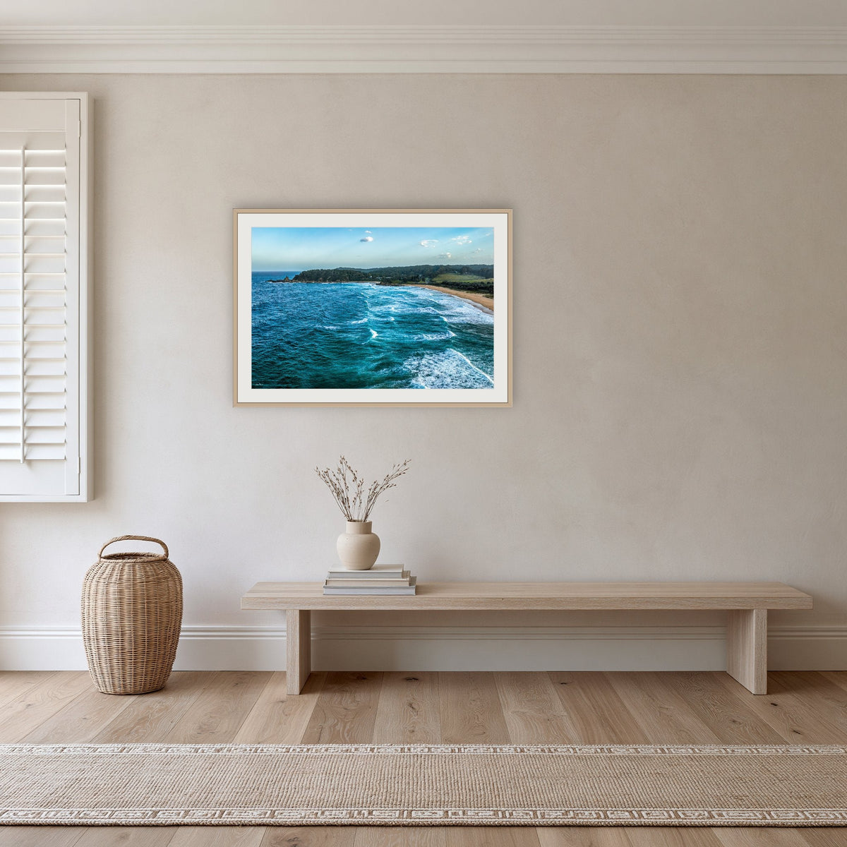 Cuttagee Beach framed print in oak with a white mat, in a hallway