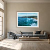 Cuttagee Beach framed print in oak with a white mat, above a dusty blue linen sofa in a lounge room