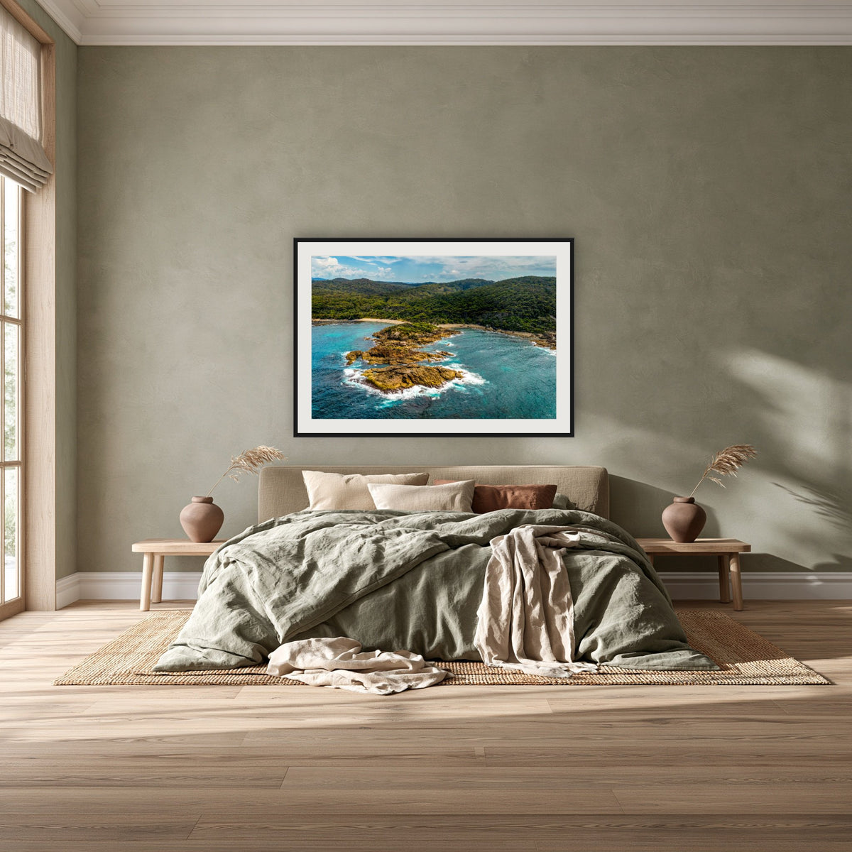 Mimosa Rocks framed print in black with a white mat, above a khaki linen bed against a green-grey wall in a bedroom