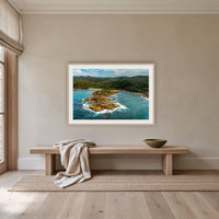 Mimosa Rocks framed print in oak with a white mat, above an oak bench in a hallway