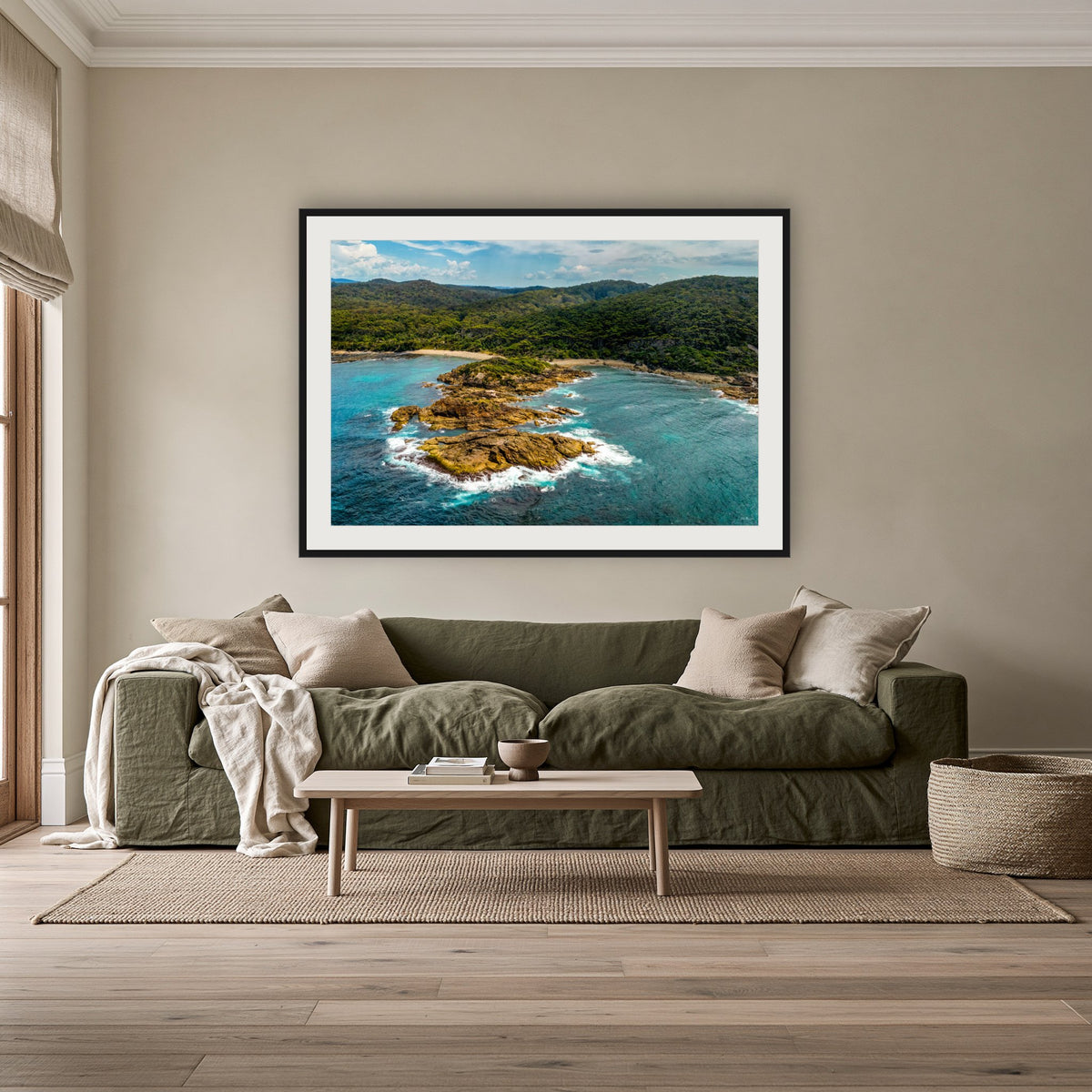 Mimosa Rocks framed print in black with a white mat, above an olive linen sofa in a lounge room