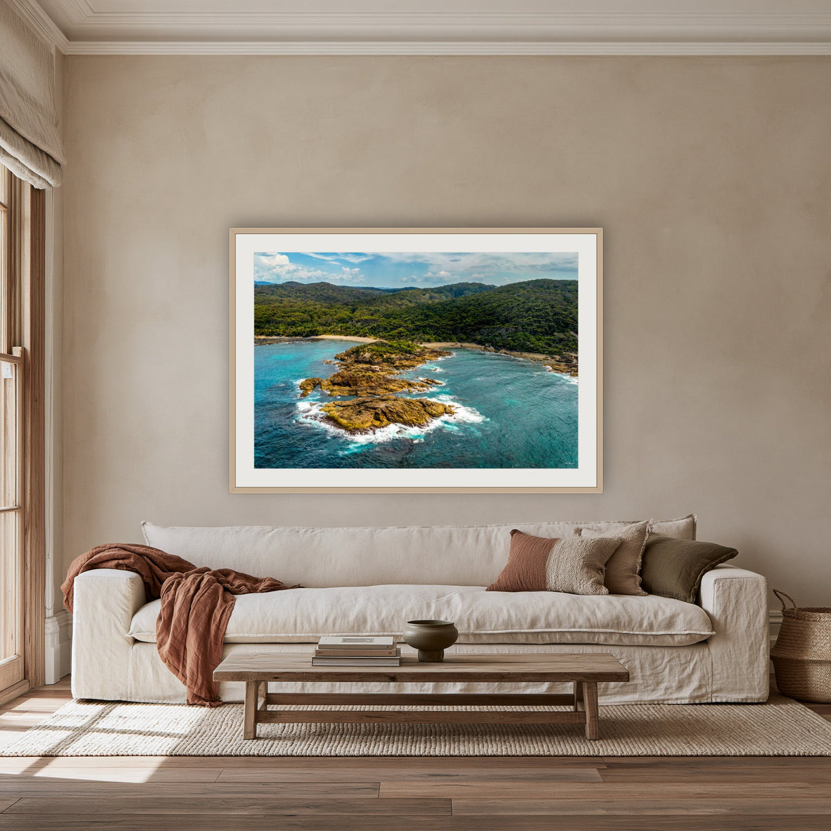 Mimosa Rocks framed print in oak with a white mat, above an oatmeal linen sofa in a lounge room