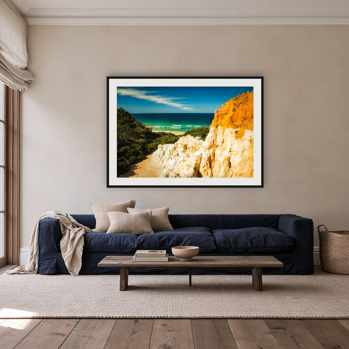 The Pinnacles framed print in black with a white mat, above a navy linen sofa in a lounge room