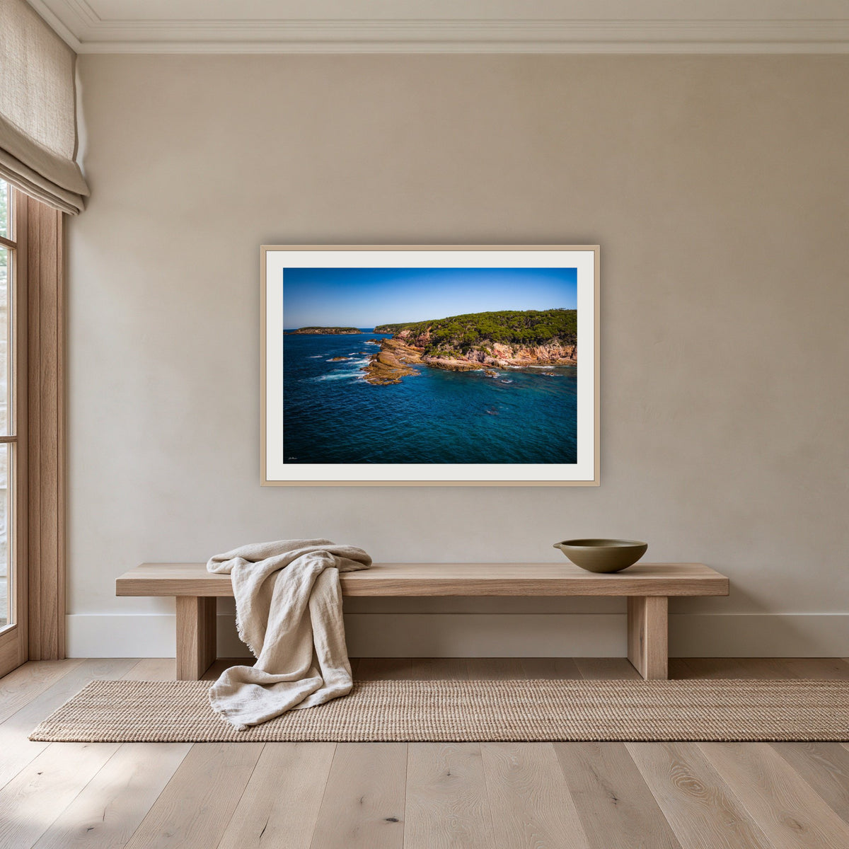 Terrace Beach framed print in oak with a white mat, above an oak bench in a hallway