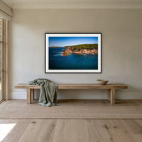 Terrace Beach framed print in black with a white mat, above an oak bench in a hallway