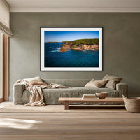 Terrace Beach framed print in black with a white mat, above a sage linen sofa in a lounge room