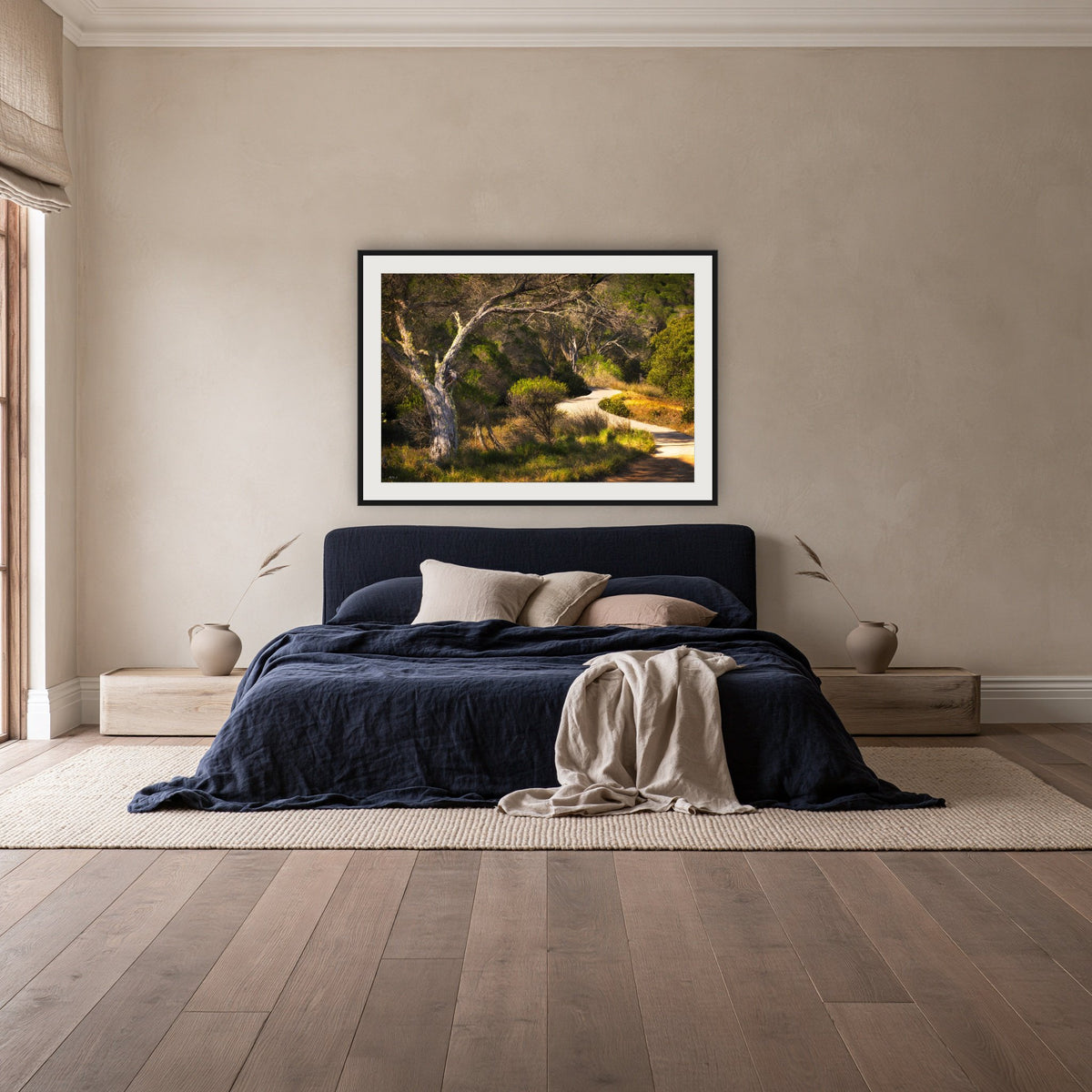 Merimbula Boardwalk framed print in black with a white mat, above a navy linen bed in a bedroom
