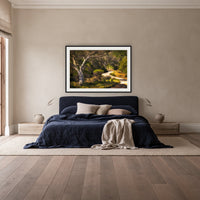 Merimbula Boardwalk framed print in black with a white mat, above a navy linen bed in a bedroom