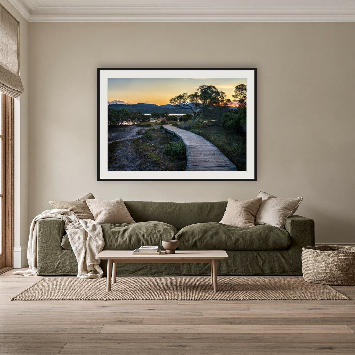 Merimbula Boardwalk at Dusk framed print in black with a white mat, above an olive linen sofa in a lounge room