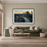 Merimbula Boardwalk at Dusk framed print in black with a white mat, above an olive linen sofa in a lounge room