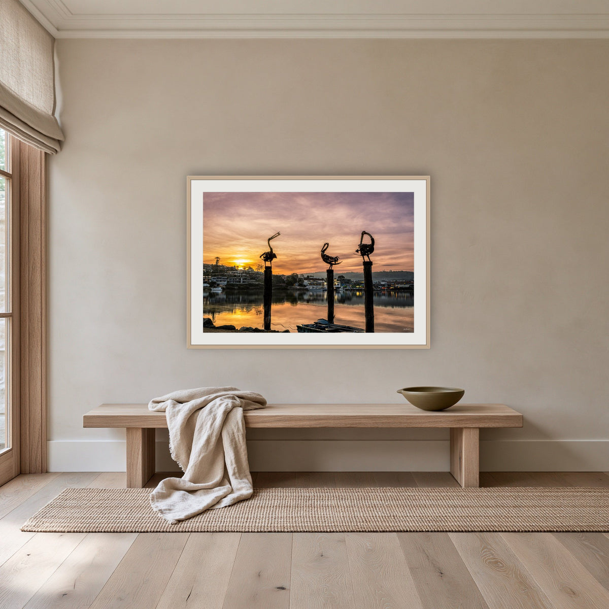 Pelican Sculptures framed print in oak with a white mat, above an oak bench in a hallway