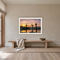 Pelican Sculptures framed print in oak with a white mat, above an oak bench in a hallway