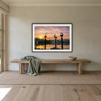 Pelican Sculptures framed print in black with a white mat, above an oak bench in a hallway