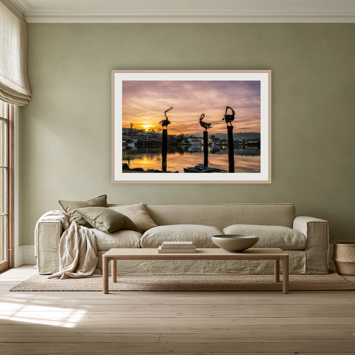 Pelican Sculptures framed print in oak with a white mat, above a linen sofa against a sage wall in a lounge room