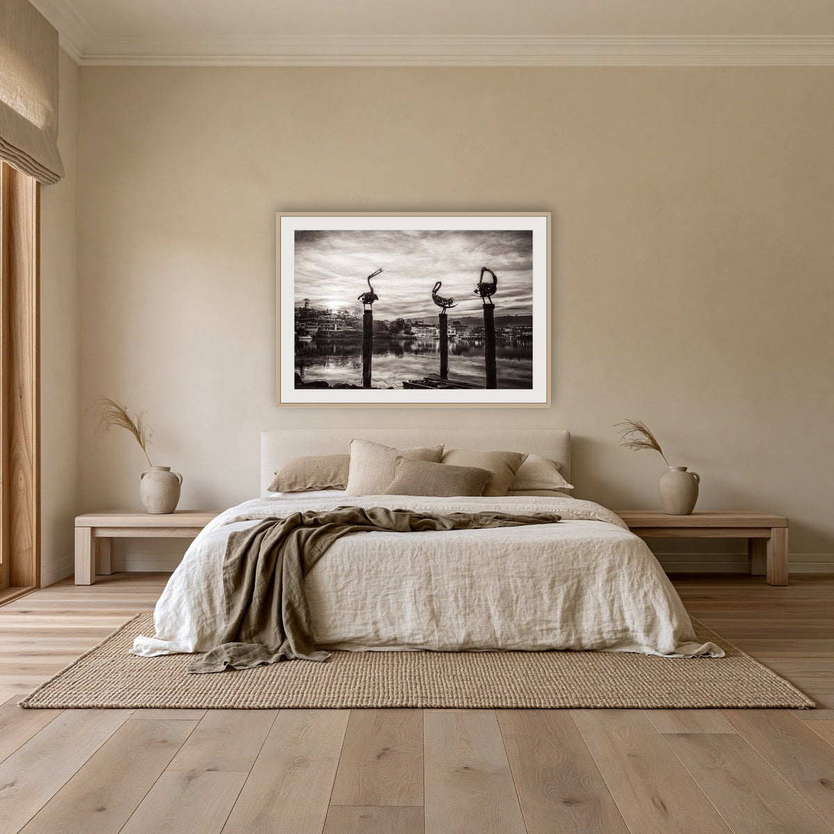 Pelican Sculptures in black and white framed print in oak with a white mat, above an oatmeal linen bed in a bedroom