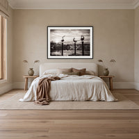 Pelican Sculptures in black and white framed print in black with a white mat, above an ivory linen bed in a bedroom