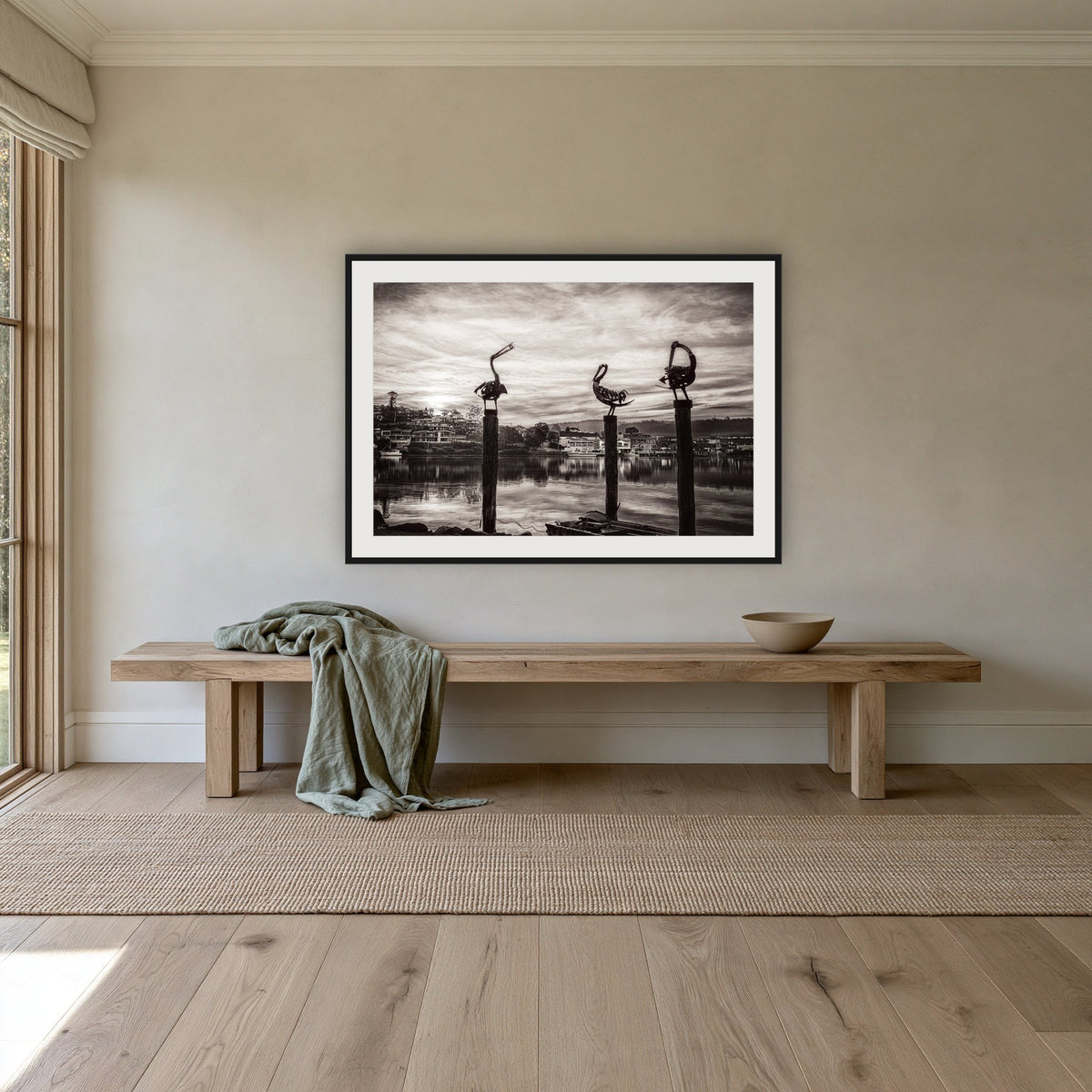 Pelican Sculptures in black and white framed print in black with a white mat, above an oak bench in a hallway