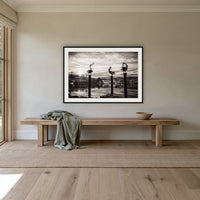 Pelican Sculptures in black and white framed print in black with a white mat, above an oak bench in a hallway