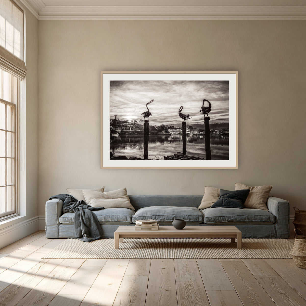 Pelican Sculptures in black and white framed print in oak with a white mat, above a dusty blue linen sofa in a lounge room