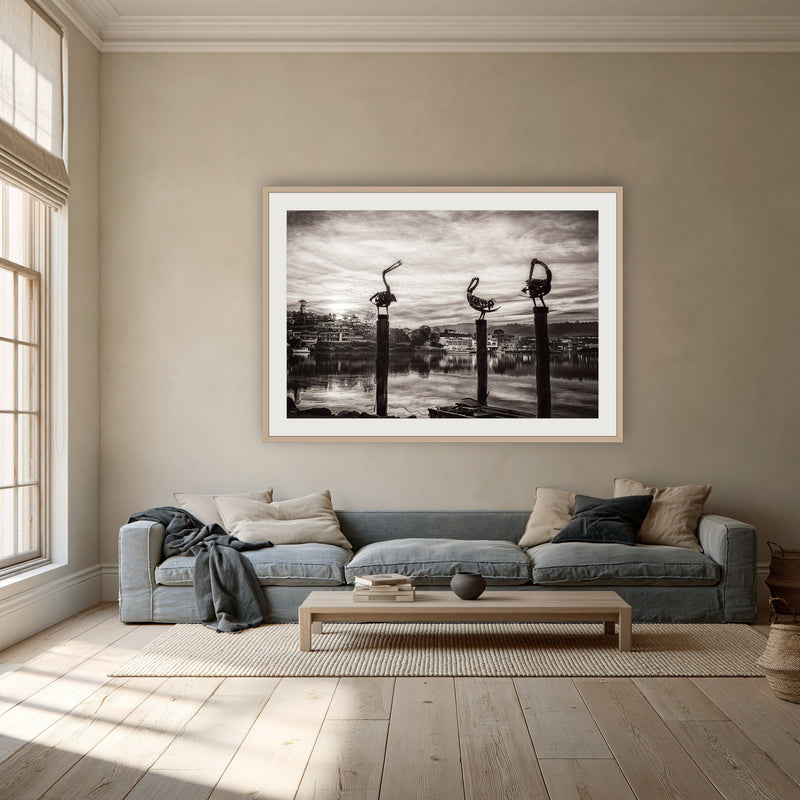 Pelican Sculptures in black and white framed print in oak with a white mat, above a dusty blue linen sofa in a lounge room