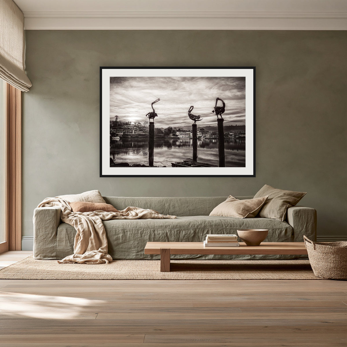 Pelican Sculptures in black and white framed print in black with a white mat, above a sage linen sofa in a lounge room