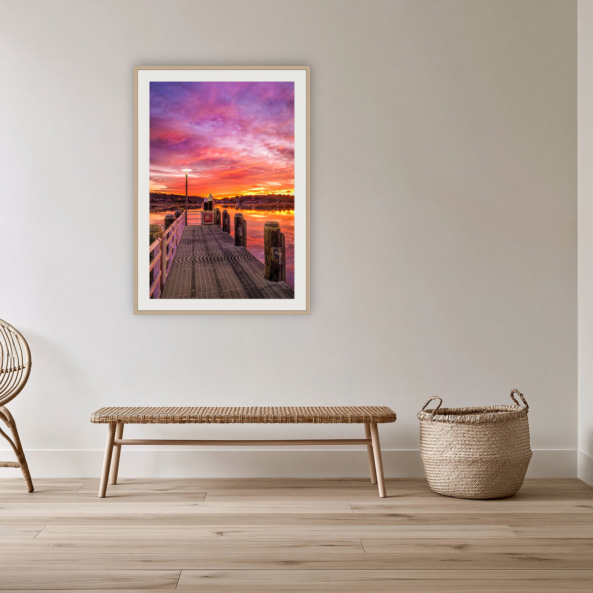 Sunrise over Merimbula Lake framed print in oak with a white mat, in a cane-panelled hallway