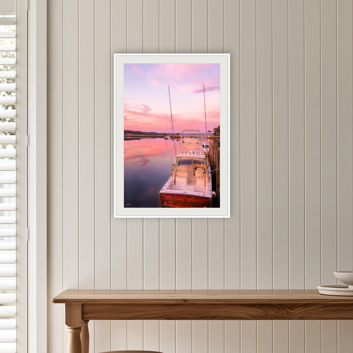 Miss Behavin framed print in white with a mat, on a panelled hallway wall
