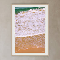 Tura Headlands framed print in oak with a white mat, in a plaster-walled hallway