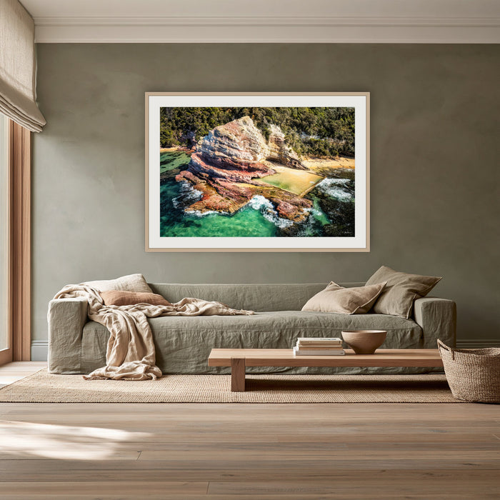 Aslings Beach Rock Pool framed print in oak with a white mat, above a sage linen sofa in a lounge room
