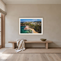 Aslings Beach from the Air framed print in oak with a white mat, above an oak bench in a hallway