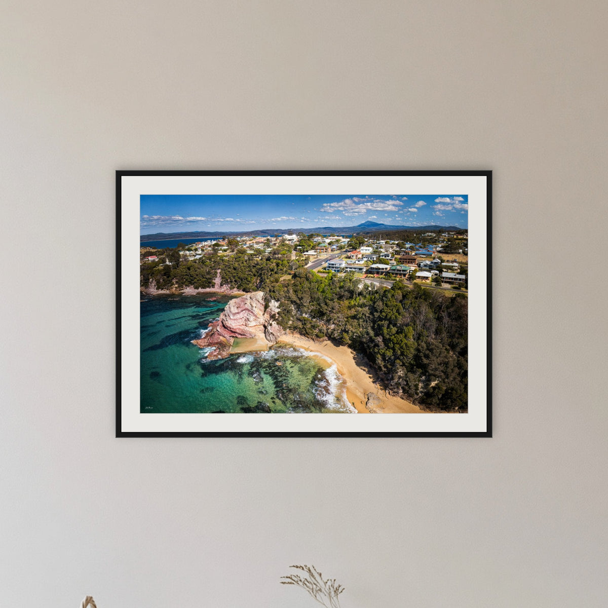 Aslings Beach from the Air framed print in black with a white mat, in a hallway