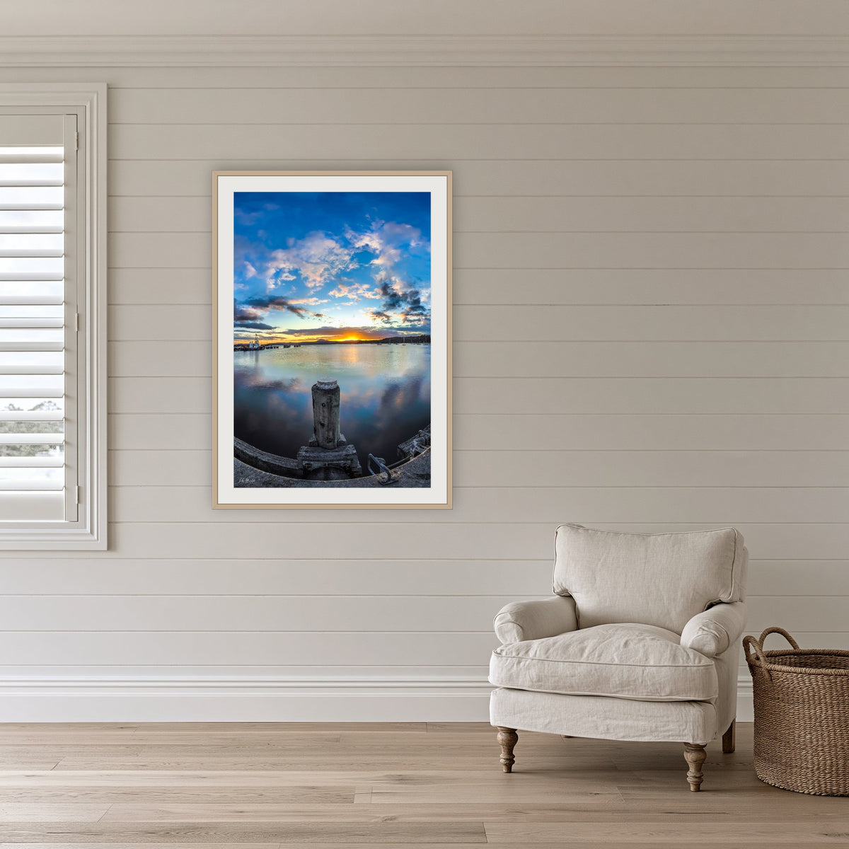 Eden Wharf Sunset framed print in oak with a white mat, on a coastal lounge room wall