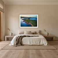 Long Point framed print in oak with a white mat, above an oatmeal linen bed in a bedroom