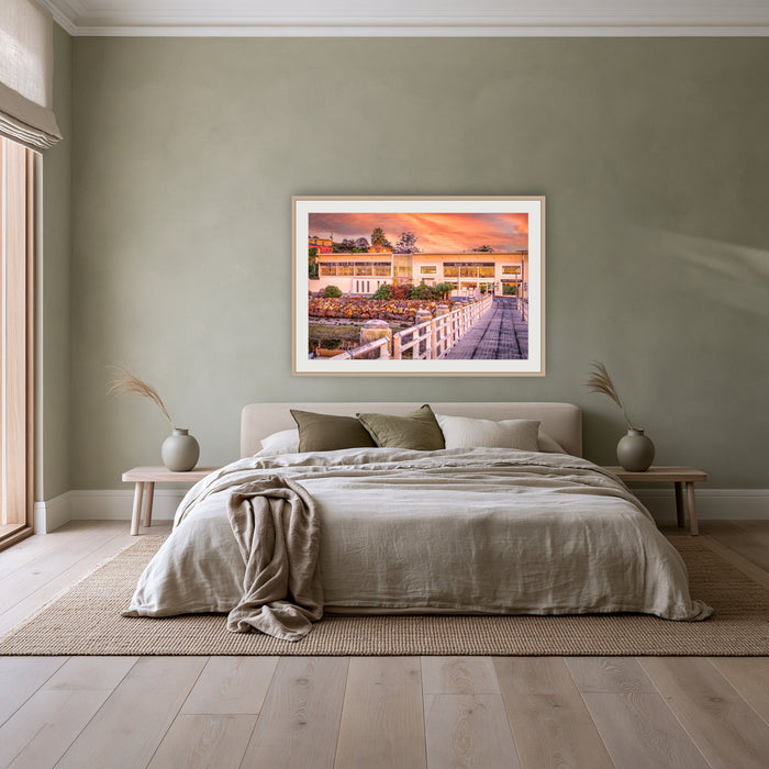 Lakeview Hotel framed print in oak with a white mat, above a linen bed against a sage wall in a bedroom