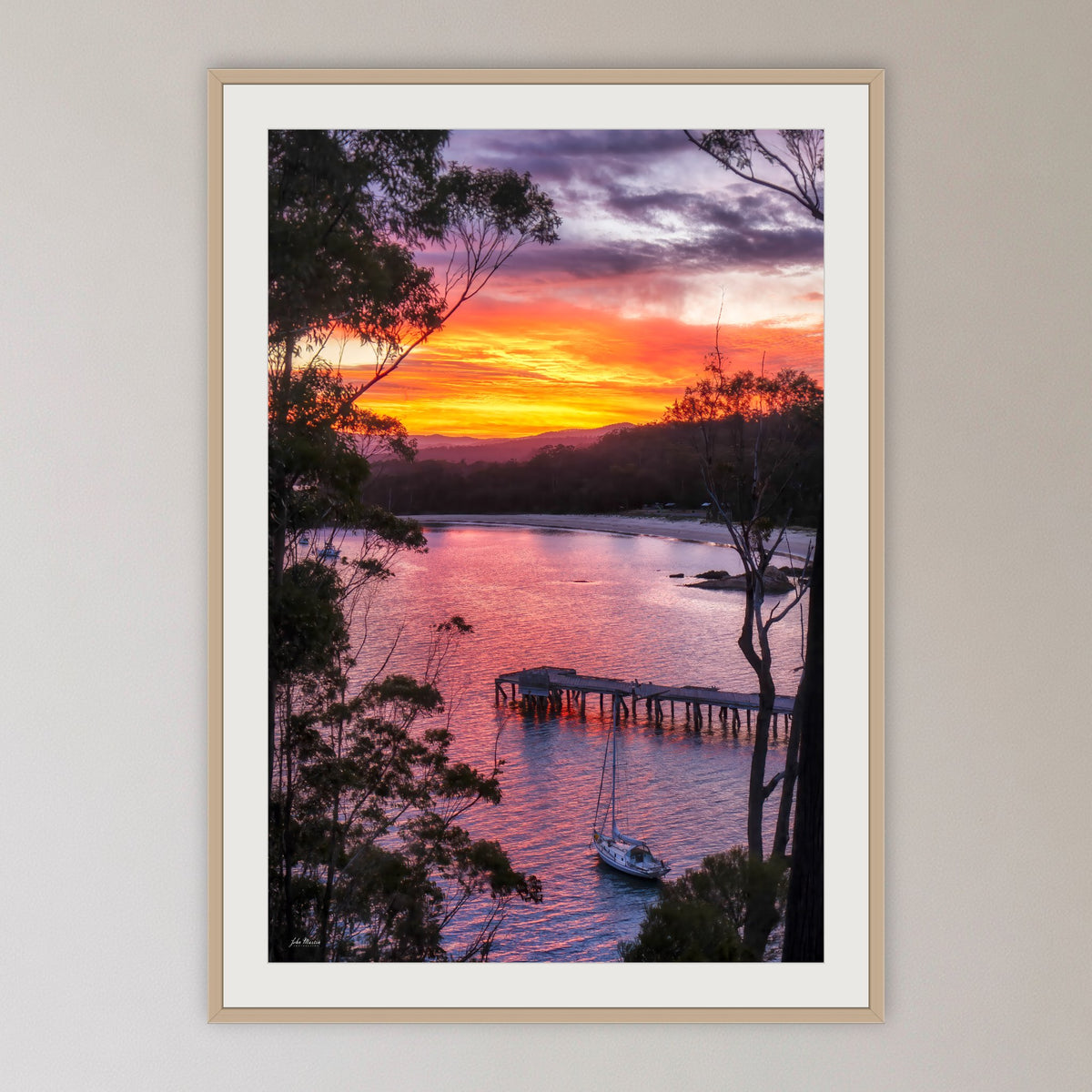 Cattle Bay framed print in oak with a white mat, in a cane-panelled hallway