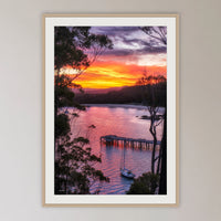 Cattle Bay framed print in oak with a white mat, in a cane-panelled hallway