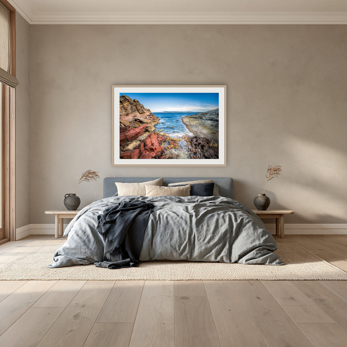 North Head Worang Point framed print in oak with a white mat, above a dusty blue linen bed in a bedroom