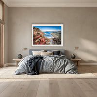 North Head Worang Point framed print in oak with a white mat, above a dusty blue linen bed in a bedroom